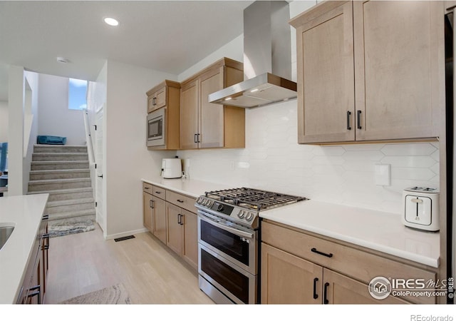 5282 Ribault St, Timnath, CO 80547 - kitchen featuring appliances with stainless steel finishes, wall chimney exhaust hood, light brown cabinetry, and recessed lighting