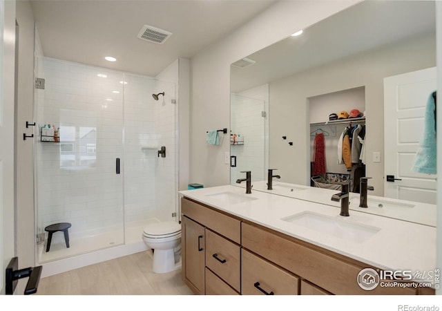 5282 Ribault St, Timnath, CO 80547 - full bathroom with a shower stall, toilet, double vanity, wood finished floors, and a walk in closet