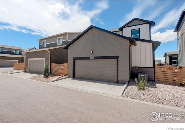 5282 Ribault St, Timnath, CO 80547 - view of front of home featuring cooling unit, concrete driveway, board and batten siding, fence, and a garage