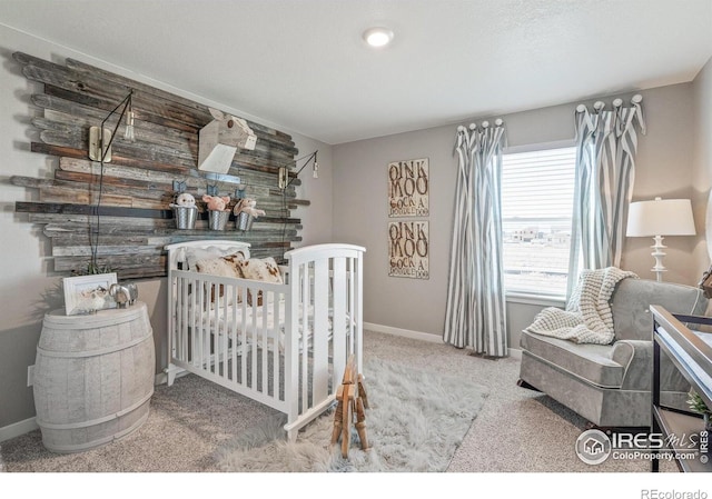 carpeted bedroom featuring baseboards and a nursery area