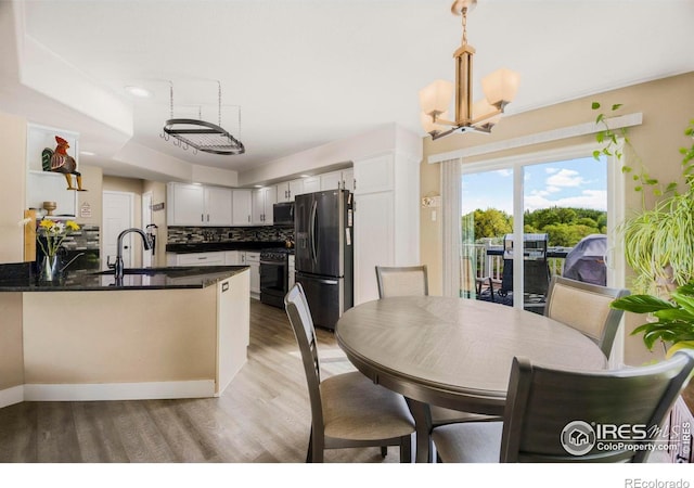 5196 32nd St, Greeley, CO 80634 - kitchen featuring black appliances, a peninsula, a chandelier, light wood finished floors, and tasteful backsplash