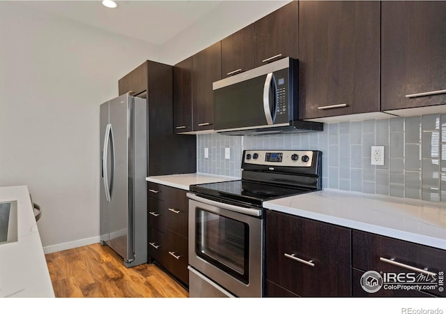 10069 Richfield St, Commerce City, CO 80022 - kitchen with appliances with stainless steel finishes, dark brown cabinetry, light countertops, backsplash, and recessed lighting