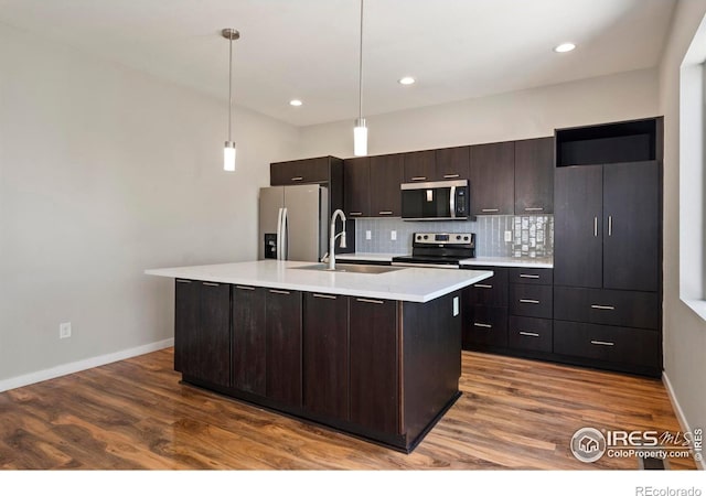 10069 Richfield St, Commerce City, CO 80022 - kitchen featuring stainless steel appliances, a sink, light countertops, backsplash, and an island with sink
