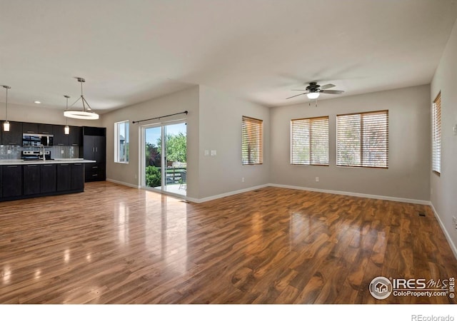 10069 Richfield St, Commerce City, CO 80022 - unfurnished living room with wood finished floors, baseboards, and ceiling fan