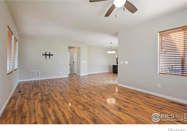 10069 Richfield St, Commerce City, CO 80022 - unfurnished living room featuring wood finished floors, a ceiling fan, and baseboards