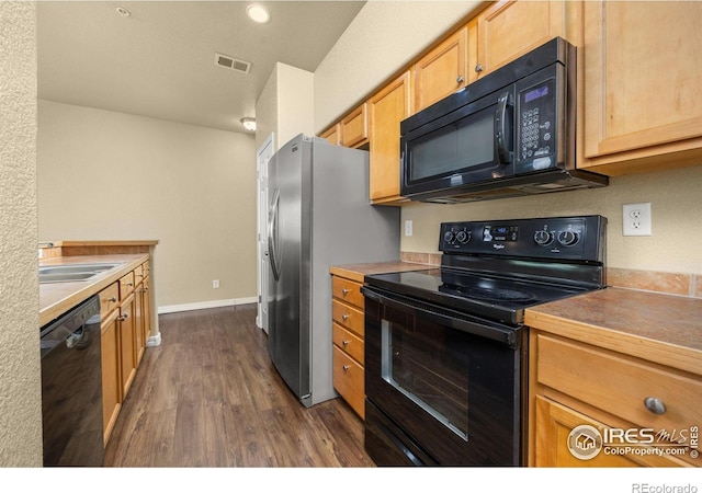 kitchen featuring black appliances, dark wood finished floors, a sink, and baseboards