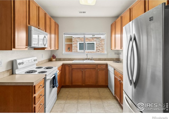 kitchen featuring white appliances, a sink, plenty of natural light, and light countertops