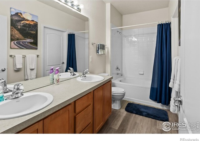 bathroom with wood finished floors, toilet, shower / bath combination with curtain, and double vanity
