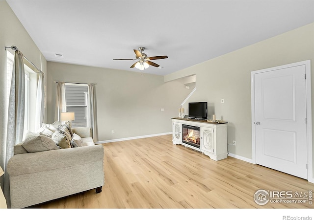 6008 Sandstone Cir, Frederick, CO 80516 - living area with a ceiling fan, light wood-style flooring, baseboards, and a glass covered fireplace