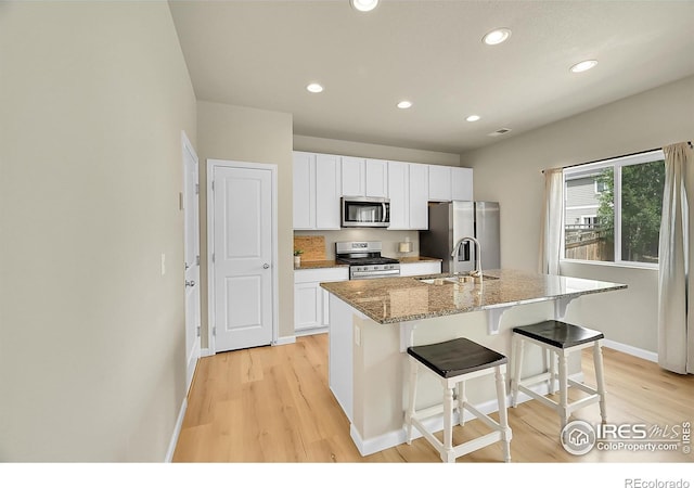 6008 Sandstone Cir, Frederick, CO 80516 - kitchen featuring stainless steel appliances, a sink, light wood-style floors, an island with sink, and recessed lighting