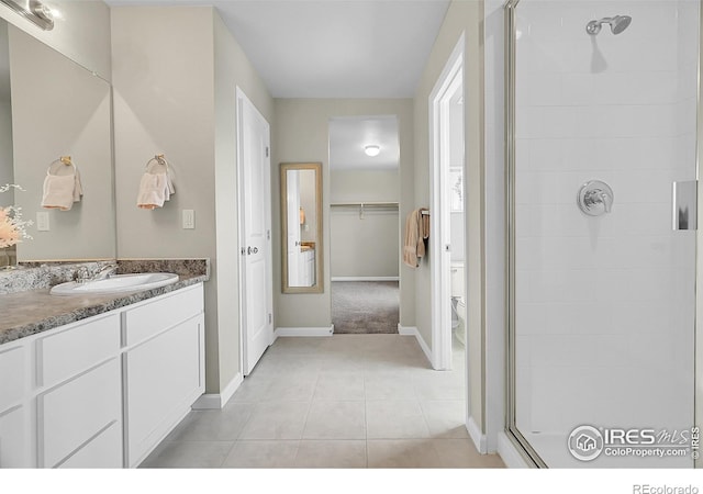 6008 Sandstone Cir, Frederick, CO 80516 - bathroom with a shower stall, toilet, vanity, tile patterned flooring, and a walk in closet