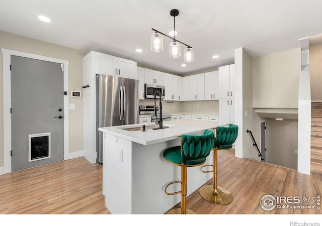 312 21st Avenue Ct, Greeley, CO 80631 - kitchen featuring stainless steel appliances, light wood-style floors, white cabinetry, light countertops, and a kitchen bar