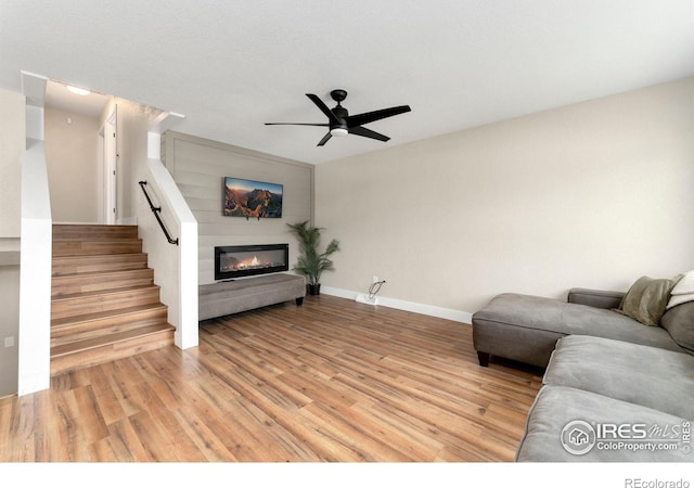 312 21st Avenue Ct, Greeley, CO 80631 - living room with light wood-style floors, ceiling fan, a glass covered fireplace, baseboards, and stairway