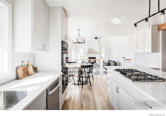 4932 Valkyrie Dr, Boulder, CO 80301 - kitchen with appliances with stainless steel finishes, light wood-type flooring, decorative backsplash, white cabinets, and recessed lighting