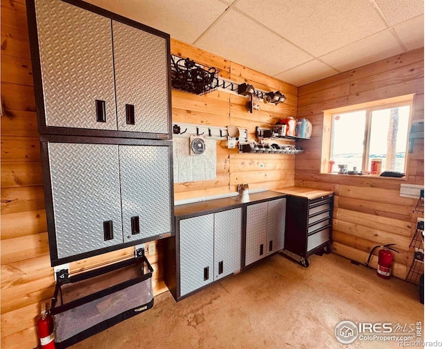 867 Windy Ridge Rd, Red Feather Lakes, CO 80545 - kitchen featuring a drop ceiling, unfinished concrete flooring, white cabinets, and wood walls