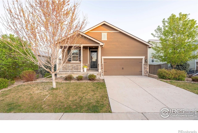 1358 14th Ave, Longmont, CO 80501 - view of front of home with covered porch, a front yard, concrete driveway, and stone siding