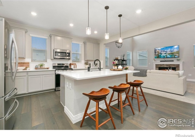 1203 Cabot Ct, Fort Collins, CO 80526 - kitchen with appliances with stainless steel finishes, dark wood-style flooring, light countertops, a kitchen bar, and recessed lighting