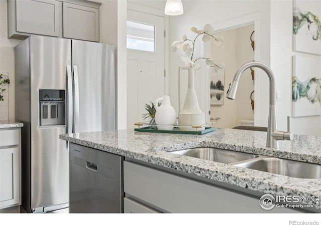 18722 E 99th Ave, Commerce City, CO 80022 - kitchen featuring appliances with stainless steel finishes, gray cabinetry, a sink, and light stone countertops