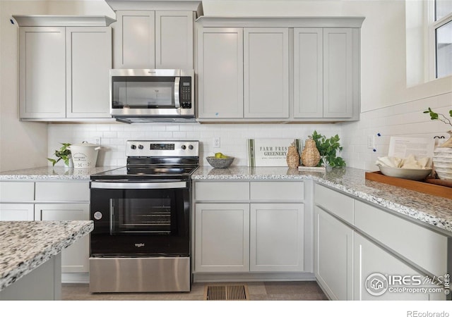 18722 E 99th Ave, Commerce City, CO 80022 - kitchen featuring appliances with stainless steel finishes, tasteful backsplash, and light stone counters