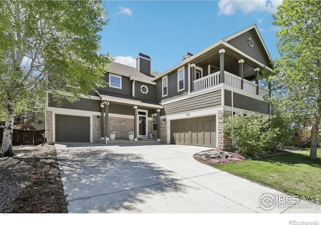 4109 Frederick Cir, Longmont, CO 80503 - view of front of home with a garage, driveway, a balcony, stone siding, and a chimney