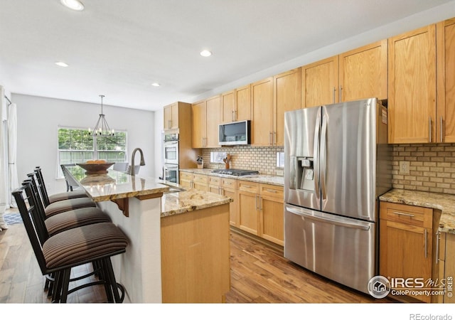 4109 Frederick Cir, Longmont, CO 80503 - kitchen with stainless steel appliances, light wood-style flooring, backsplash, recessed lighting, and a breakfast bar