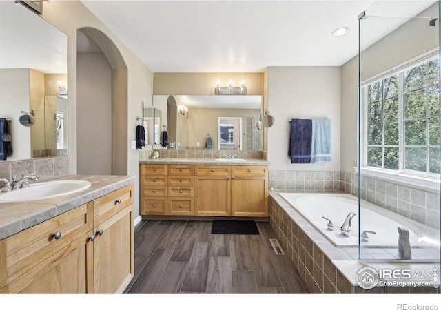 4109 Frederick Cir, Longmont, CO 80503 - full bathroom with a bath, wood finished floors, backsplash, and two vanities