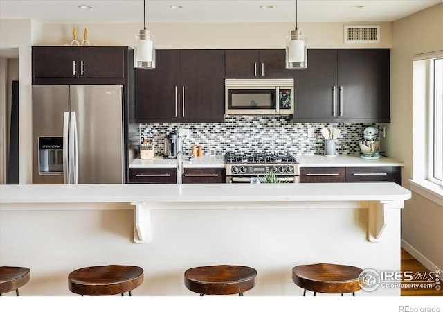 1201 Balsam Ave Unit 302, Boulder, CO 80304 - kitchen featuring stainless steel appliances, light countertops, a breakfast bar, tasteful backsplash, and dark brown cabinetry