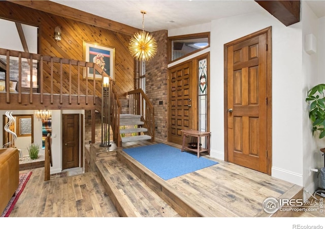 4456 W Pioneer Dr, Greeley, CO 80634 - entryway featuring wood finished floors, stairs, a chandelier, wood walls, and baseboards