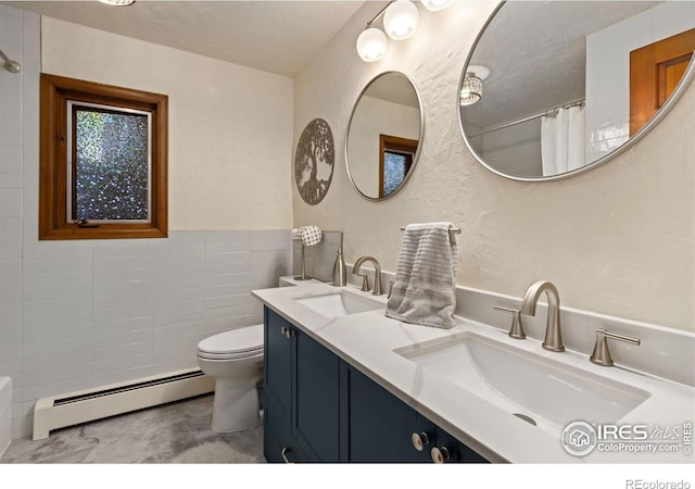 4456 W Pioneer Dr, Greeley, CO 80634 - bathroom with baseboard heating, toilet, a textured wall, double vanity, and tile walls