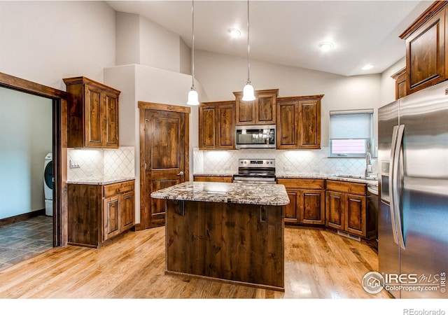 3570 Saguaro Dr, Loveland, CO 80537 - kitchen with stainless steel appliances, light stone counters, backsplash, light wood-type flooring, and high vaulted ceiling