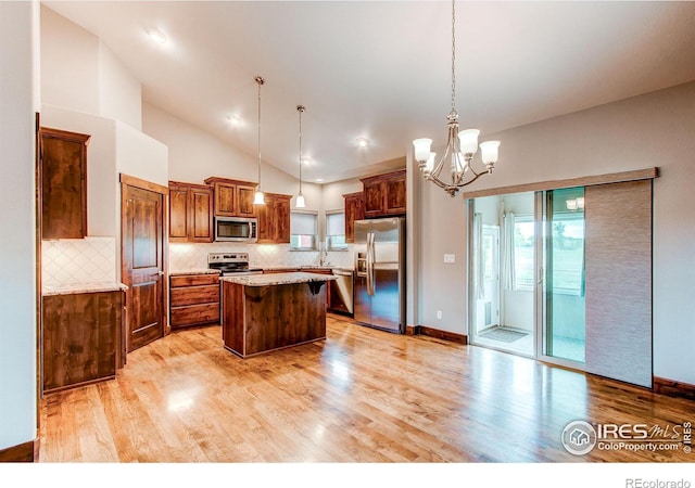 3570 Saguaro Dr, Loveland, CO 80537 - kitchen with appliances with stainless steel finishes, a center island, light wood-type flooring, tasteful backsplash, and high vaulted ceiling