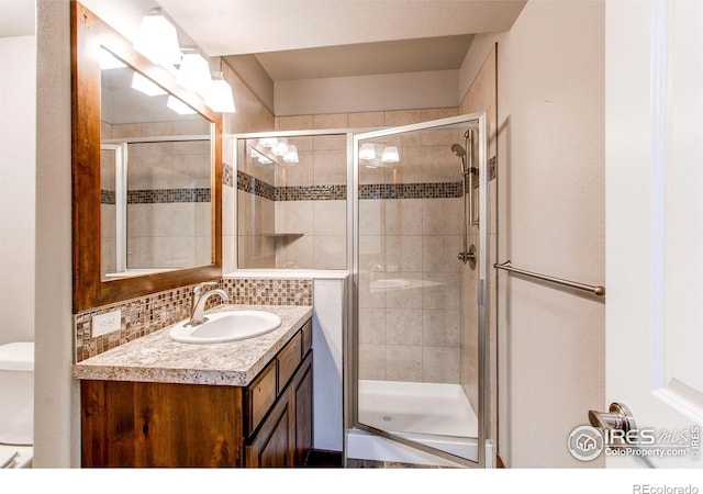 3570 Saguaro Dr, Loveland, CO 80537 - bathroom featuring a shower stall, vanity, toilet, and decorative backsplash