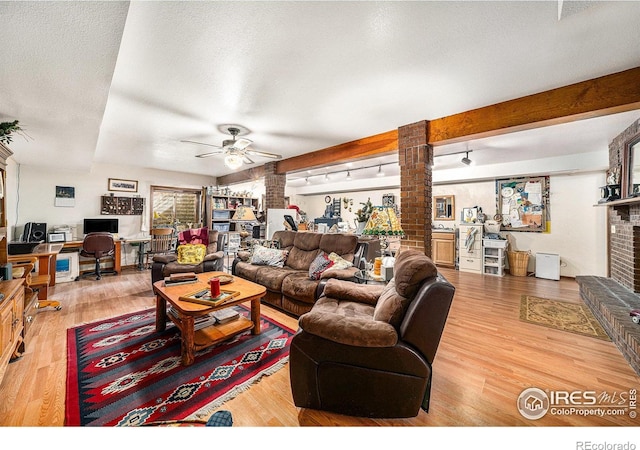 4601 N Sunshine Ct, Loveland, CO 80537 - living room with decorative columns, ceiling fan, a fireplace, wood finished floors, and a desk