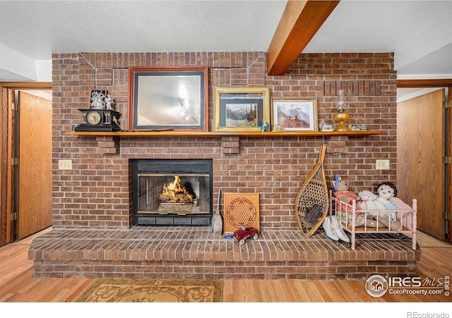 4601 N Sunshine Ct, Loveland, CO 80537 - detailed view of wood finished floors, beam ceiling, a brick fireplace, and a textured ceiling