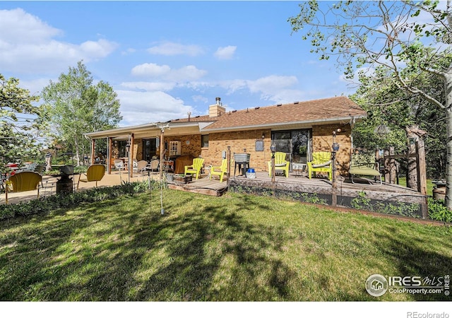4601 N Sunshine Ct, Loveland, CO 80537 - back of house featuring a yard, a deck, brick siding, and a chimney