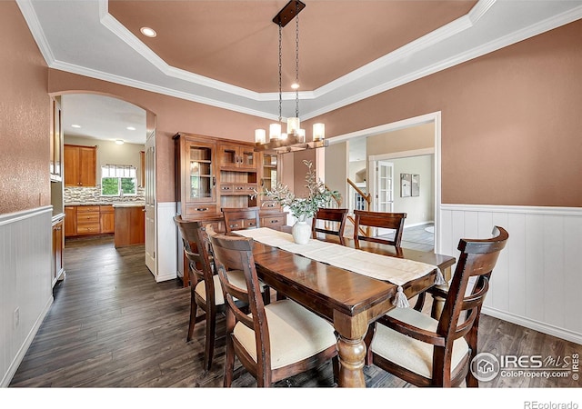 4764 Maggie Ct, Loveland, CO 80537 - dining room featuring dark wood finished floors, arched walkways, a wainscoted wall, a tray ceiling, and a chandelier