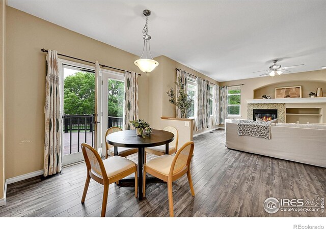4764 Maggie Ct, Loveland, CO 80537 - dining room with wood finished floors, a ceiling fan, a glass covered fireplace, and baseboards