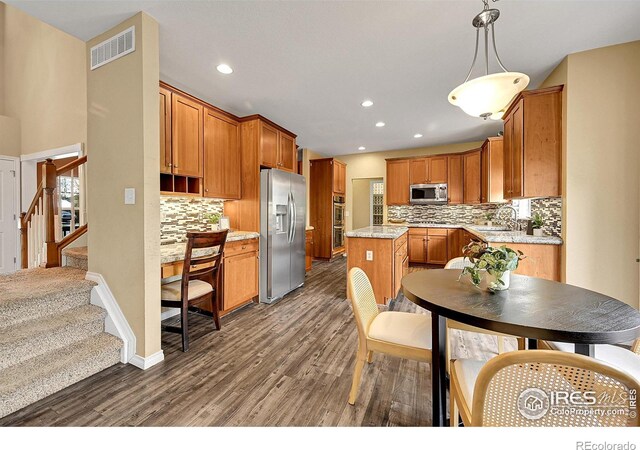 4764 Maggie Ct, Loveland, CO 80537 - kitchen with appliances with stainless steel finishes, backsplash, dark wood finished floors, a sink, and a kitchen island