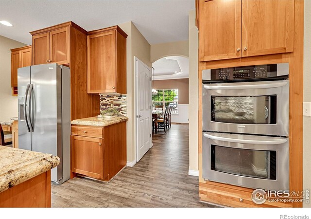 4764 Maggie Ct, Loveland, CO 80537 - kitchen with stainless steel appliances, arched walkways, light wood finished floors, recessed lighting, and light stone counters
