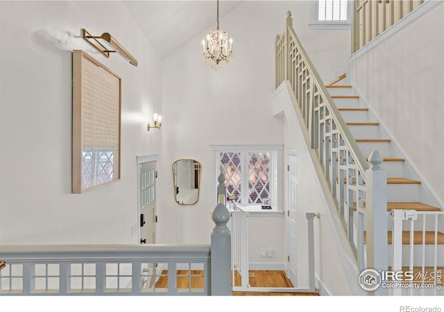 1133 Mapleton Ave, Boulder, CO 80304 - staircase featuring high vaulted ceiling, a chandelier, healthy amount of natural light, wood finished floors, and baseboards