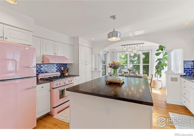 1133 Mapleton Ave, Boulder, CO 80304 - kitchen with range with gas stovetop, freestanding refrigerator, arched walkways, under cabinet range hood, and dark countertops