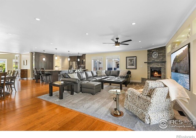 1119 Wrangler Way, Loveland, CO 80537 - living area with light wood-style flooring, a stone fireplace, a ceiling fan, recessed lighting, and baseboards
