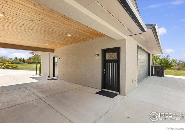 1119 Wrangler Way, Loveland, CO 80537 - entrance to property featuring concrete driveway, a garage, stucco siding, and a patio