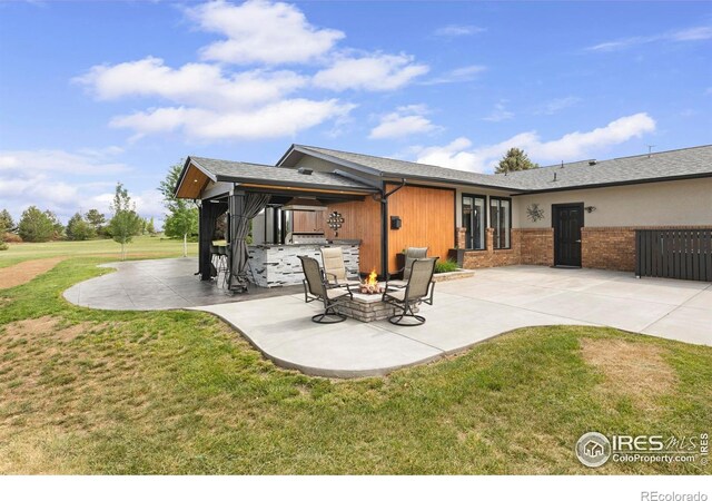 1119 Wrangler Way, Loveland, CO 80537 - rear view of property with a lawn, a patio, an outdoor fire pit, and brick siding