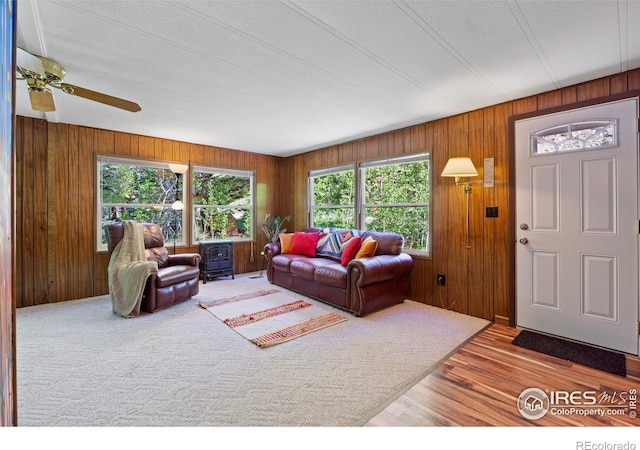 185 Meadow Ln, Bellvue, CO 80512 - living room featuring wooden walls, wood finished floors, a ceiling fan, and a wood stove