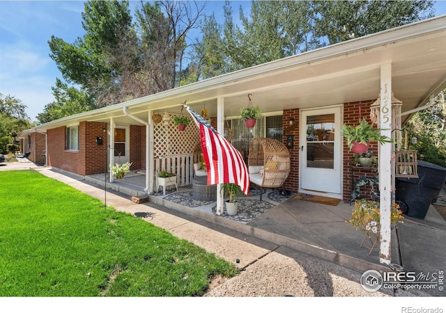 view of front facade featuring brick siding, a front lawn, and a porch