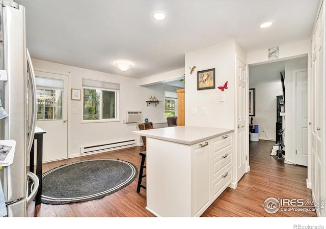 925 Columbia Rd Unit 714, Fort Collins, CO 80525 - kitchen featuring baseboard heating, freestanding refrigerator, wood finished floors, a breakfast bar area, and a wall unit AC