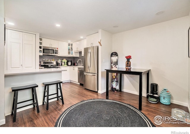 925 Columbia Rd Unit 714, Fort Collins, CO 80525 - kitchen with appliances with stainless steel finishes, dark wood-style flooring, glass insert cabinets, white cabinetry, and a kitchen bar