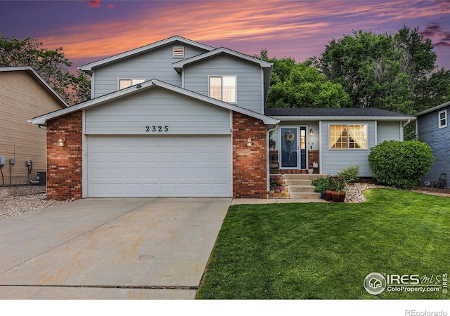 2325 42nd Avenue Ct, Greeley, CO 80634 - tri-level home with a garage, a lawn, brick siding, driveway, and central air condition unit