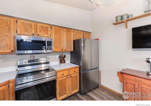 2325 42nd Avenue Ct, Greeley, CO 80634 - kitchen with appliances with stainless steel finishes, wood finished floors, light countertops, open shelves, and brown cabinetry